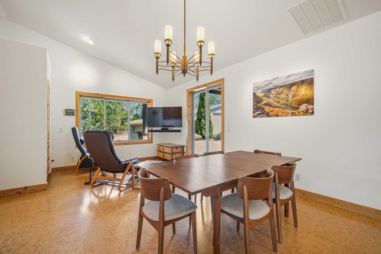 Dining area with large windows, natural light, and views toward the surrounding trees and landscaping.