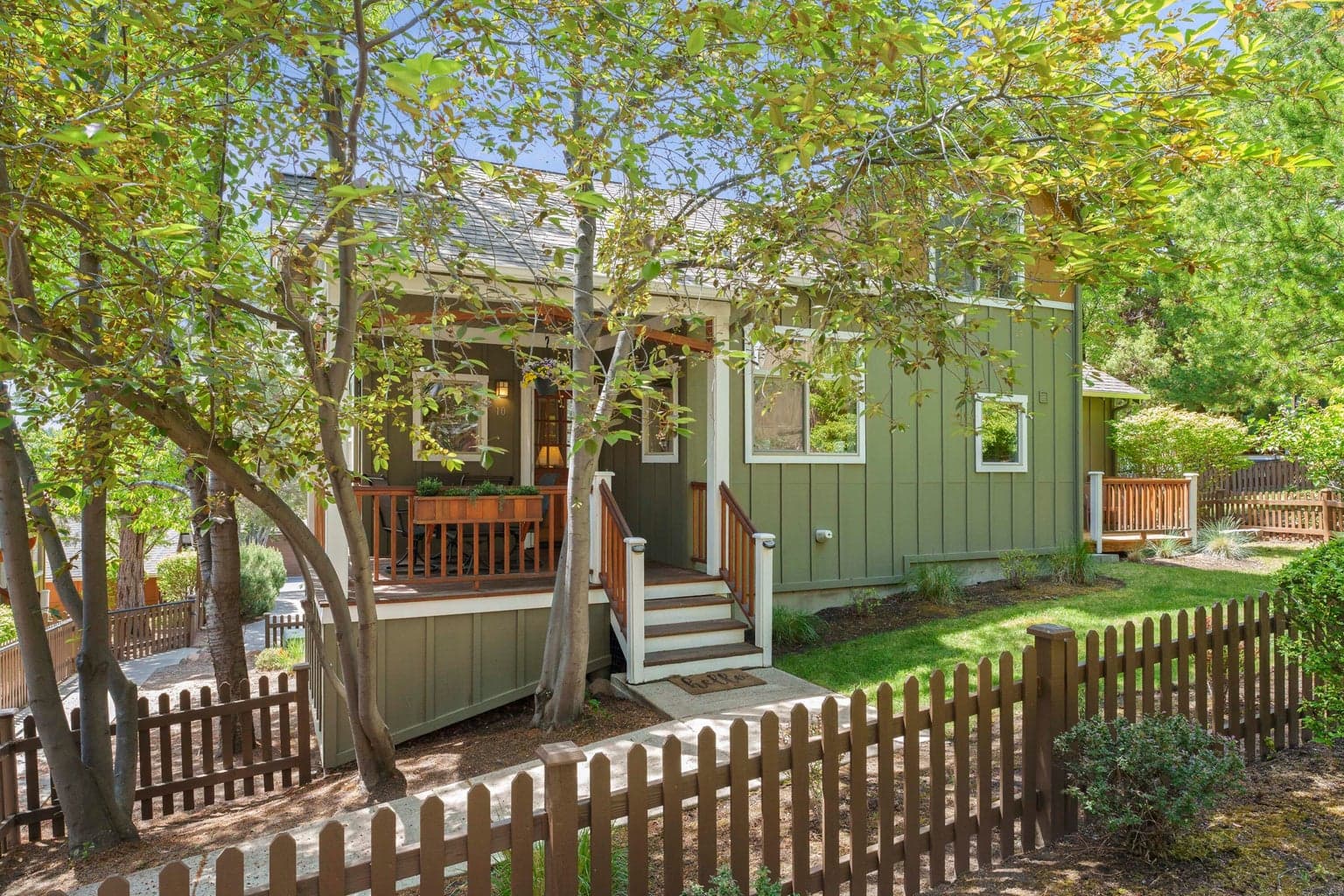 Fenced yard with covered porch in front and open deck off Primary Bedroom