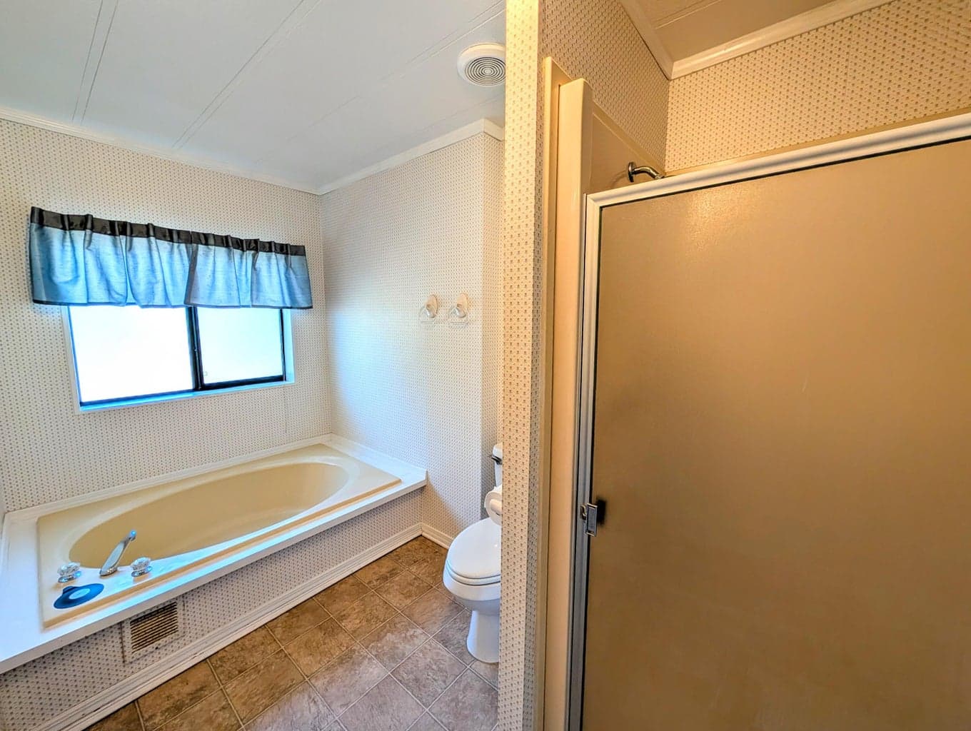 Roomy primary bathroom with double vanity, tub and shower