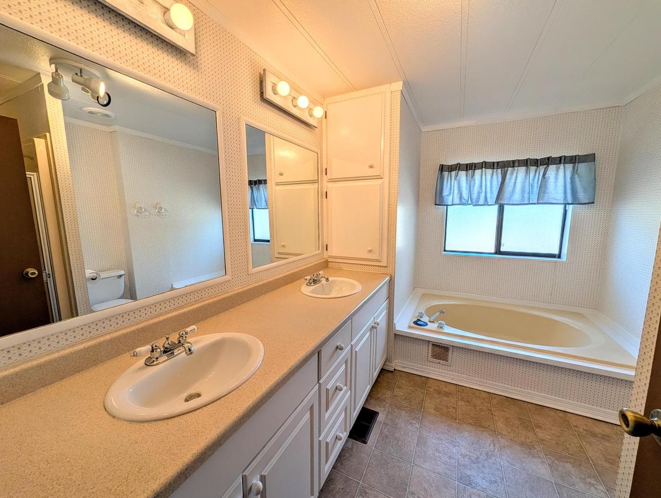 Roomy primary bathroom with double vanity, tub and shower