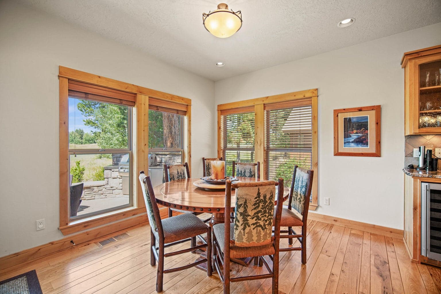 Light-filled breakfast nook with wood-wrapped windows and views toward the patio and natural landscape.