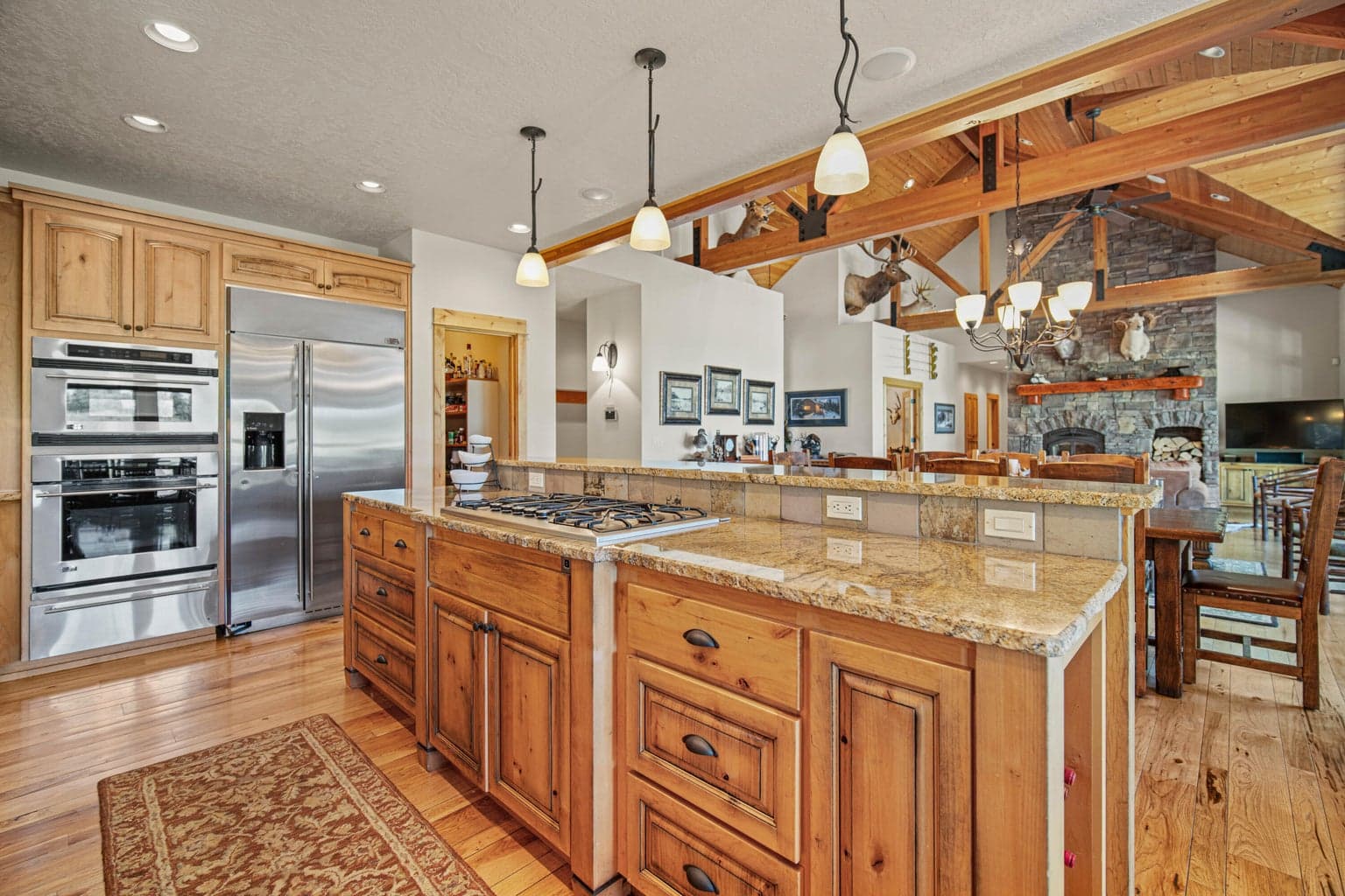 Granite island, gas cooktop, custom cabinetry, and open sightlines to the great room and fireplace.