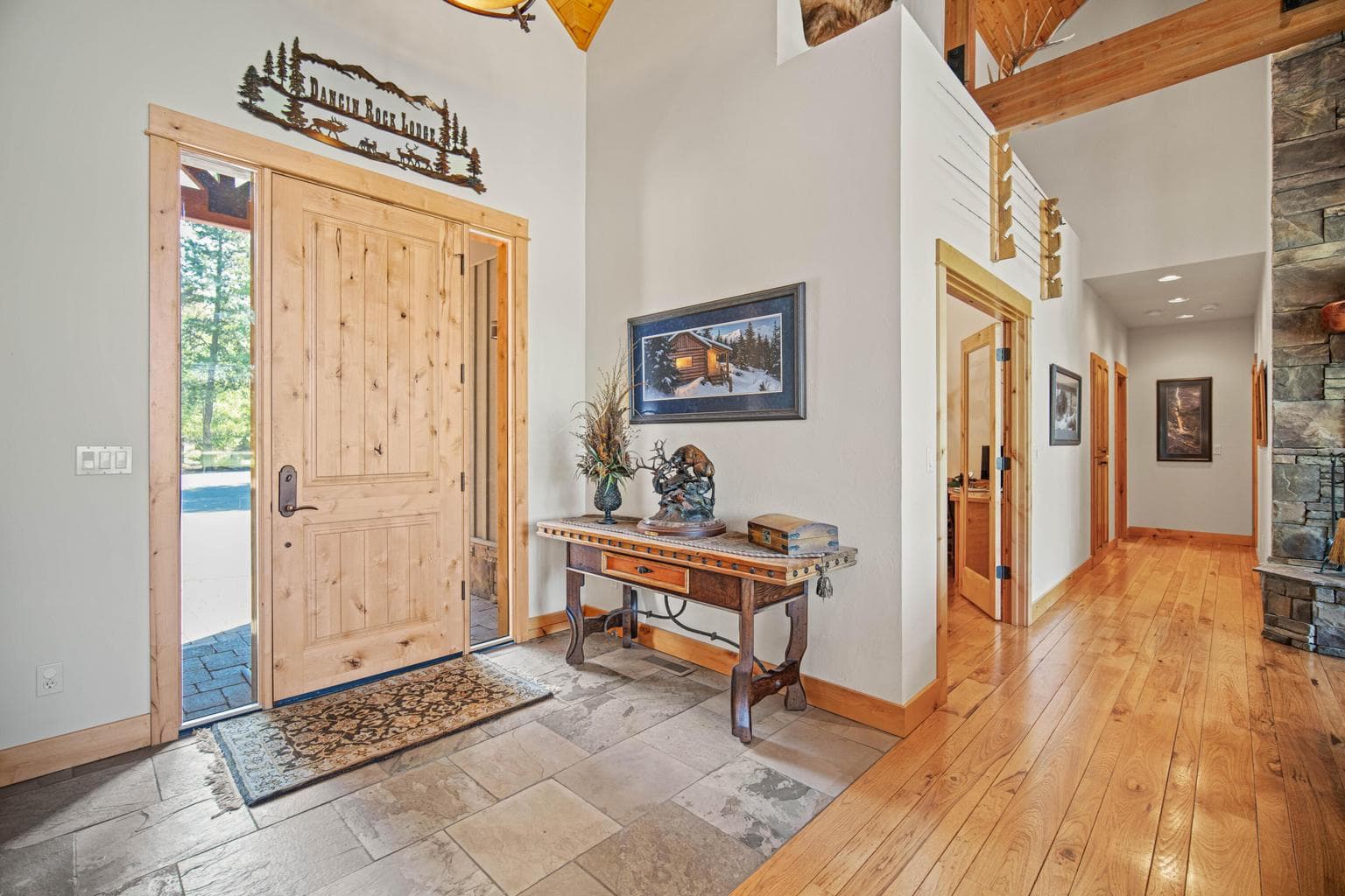 Welcoming entry with slate tile, hardwood floors, natural wood trim, and immediate connection to the home’s lodge-inspired style.