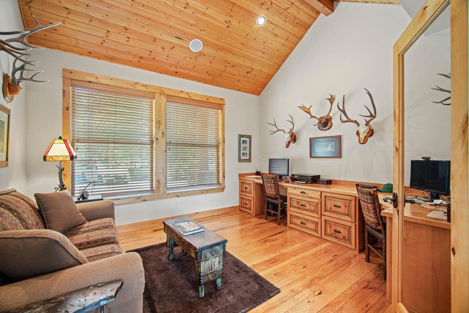 Main-level den or office with vaulted wood ceiling, hardwood floors, built-ins, and a quiet location near the great room.