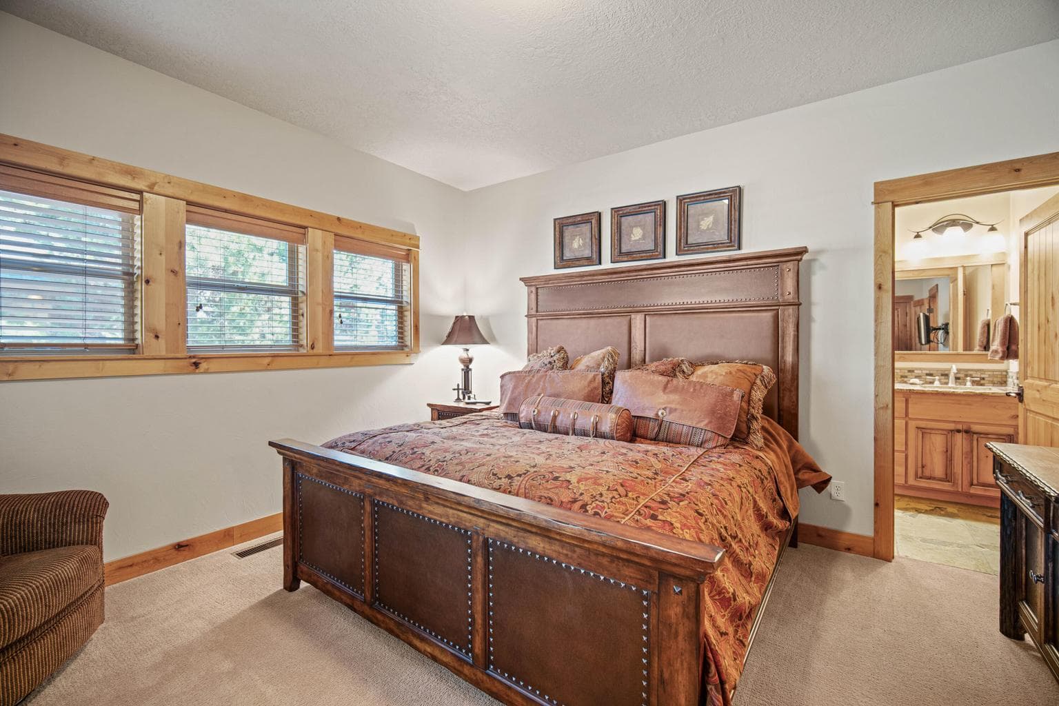 Comfortable main-level guest suite one with wood-trimmed windows, neutral finishes, and direct access to the en-suite bath.
