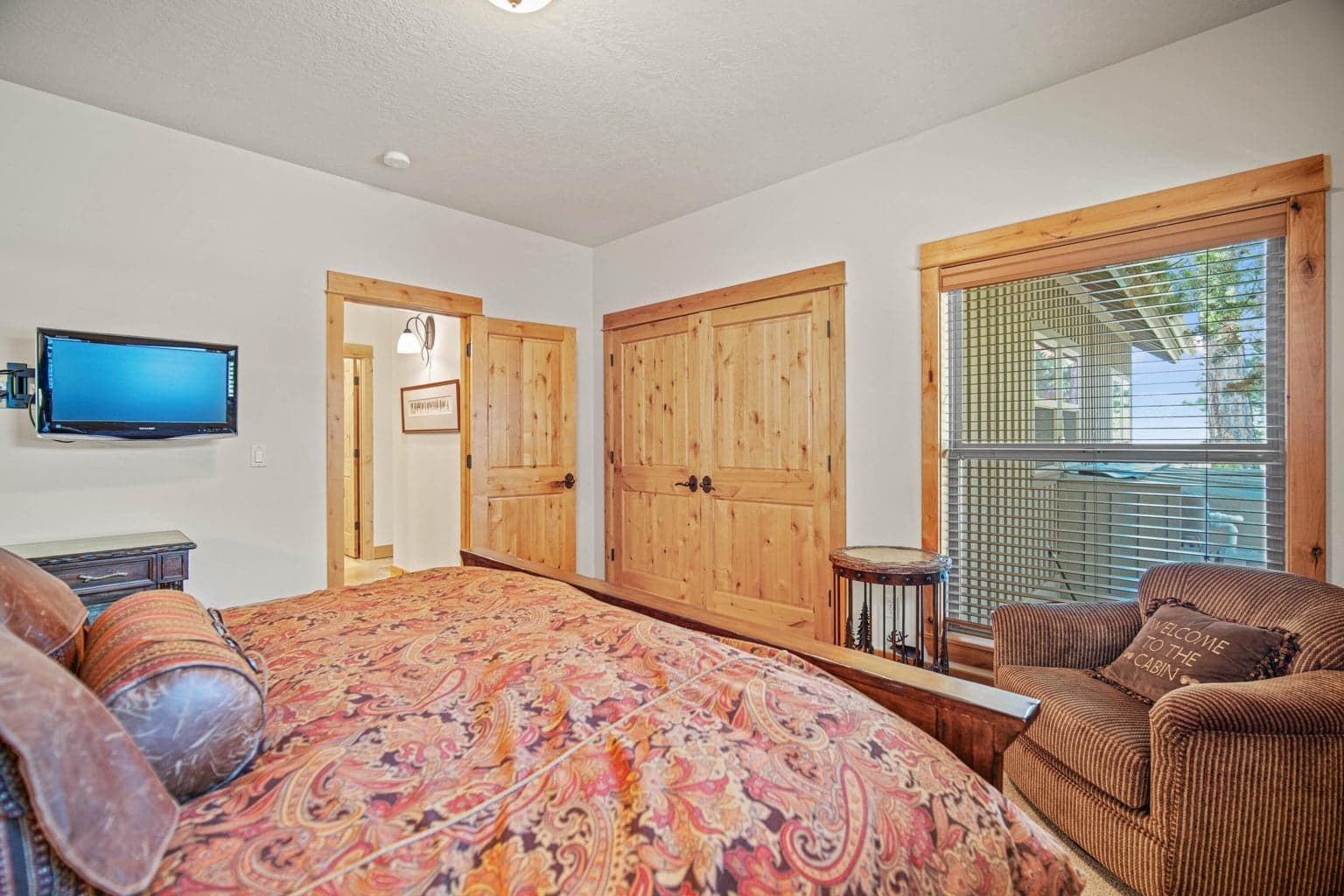 Guest suite view showing generous wood closet doors, seating area, and connection to the private bath.