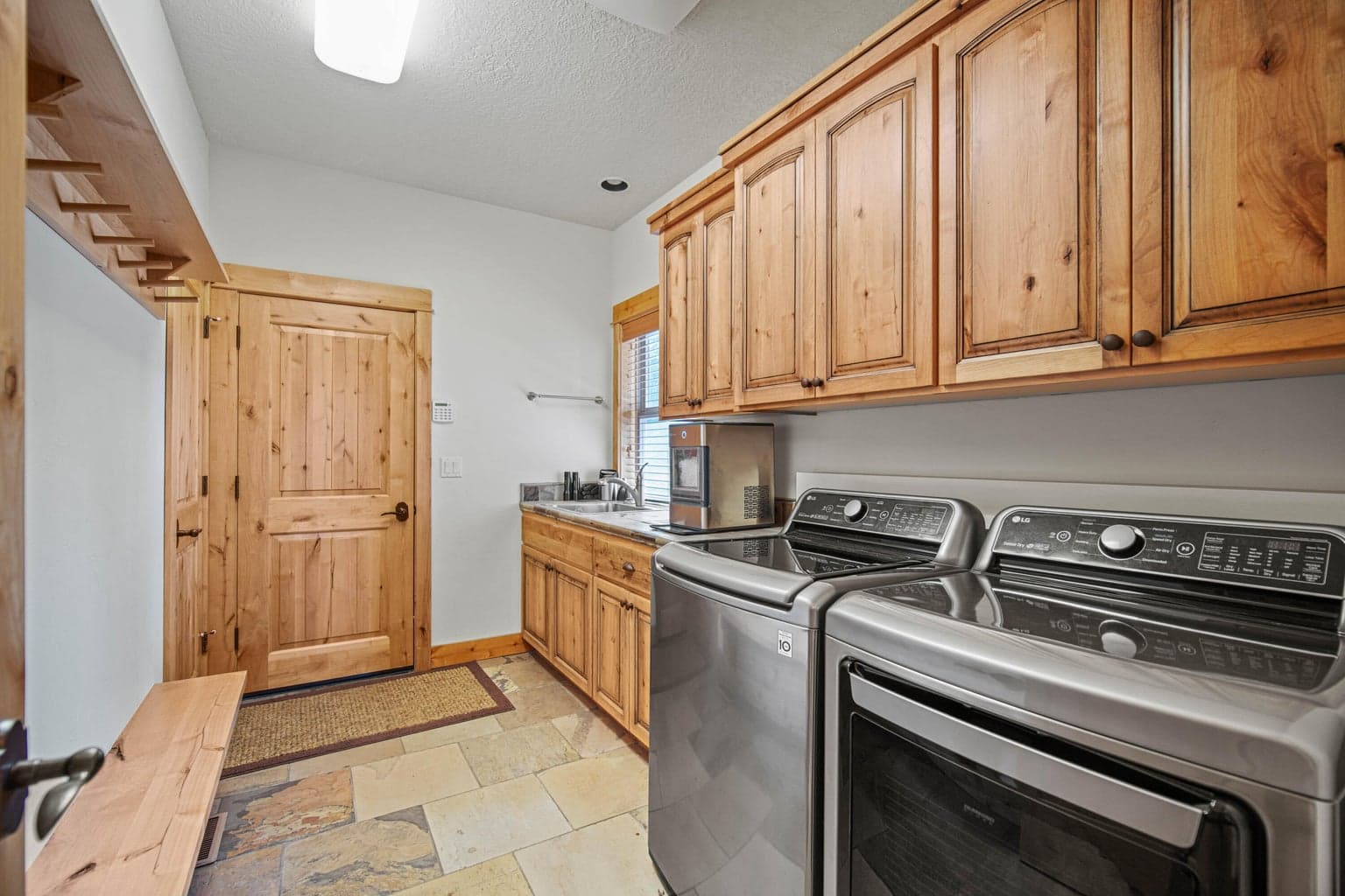Laundry and mud room with cabinetry, utility sink, exterior access, and durable tile flooring for active Central Oregon living.