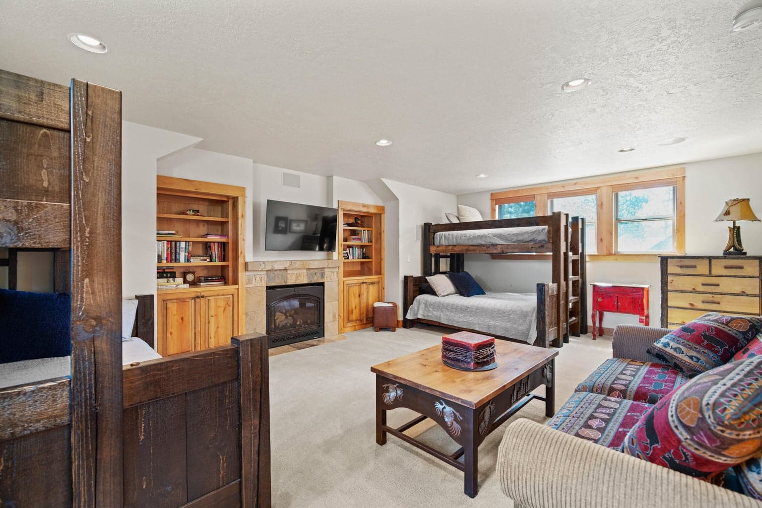 Flexible bonus room with fireplace, built-in shelving, bunk sleeping areas, and comfortable gathering space.