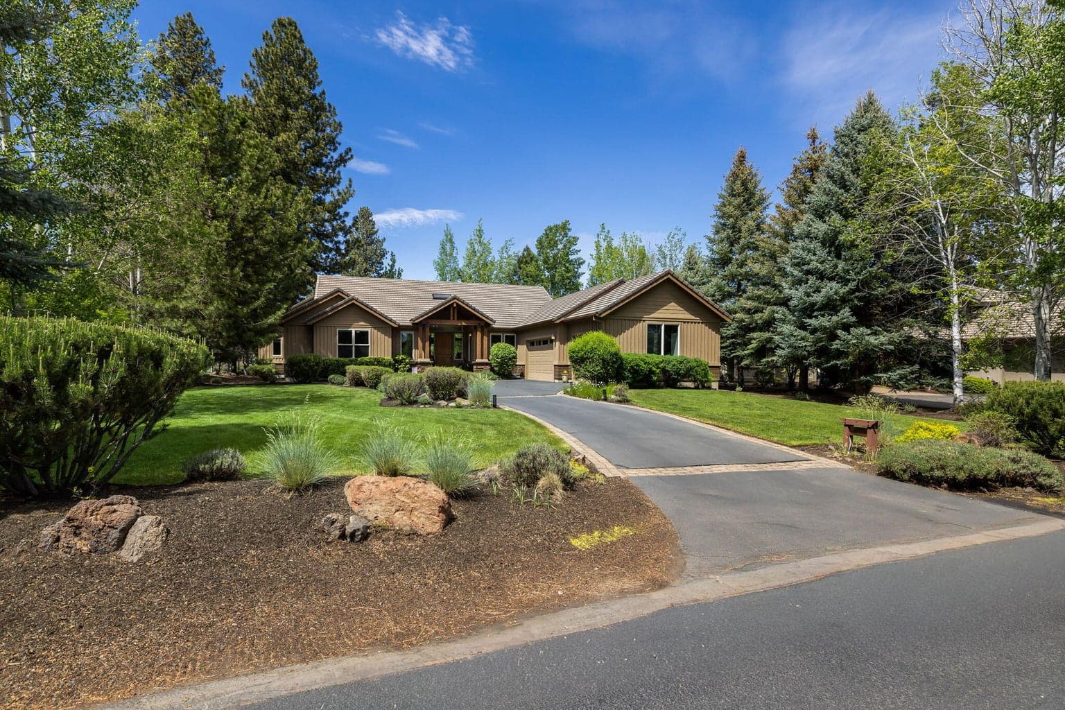 A welcoming approach with manicured grounds, mature landscaping, and a generous driveway leading to the three-car garage.