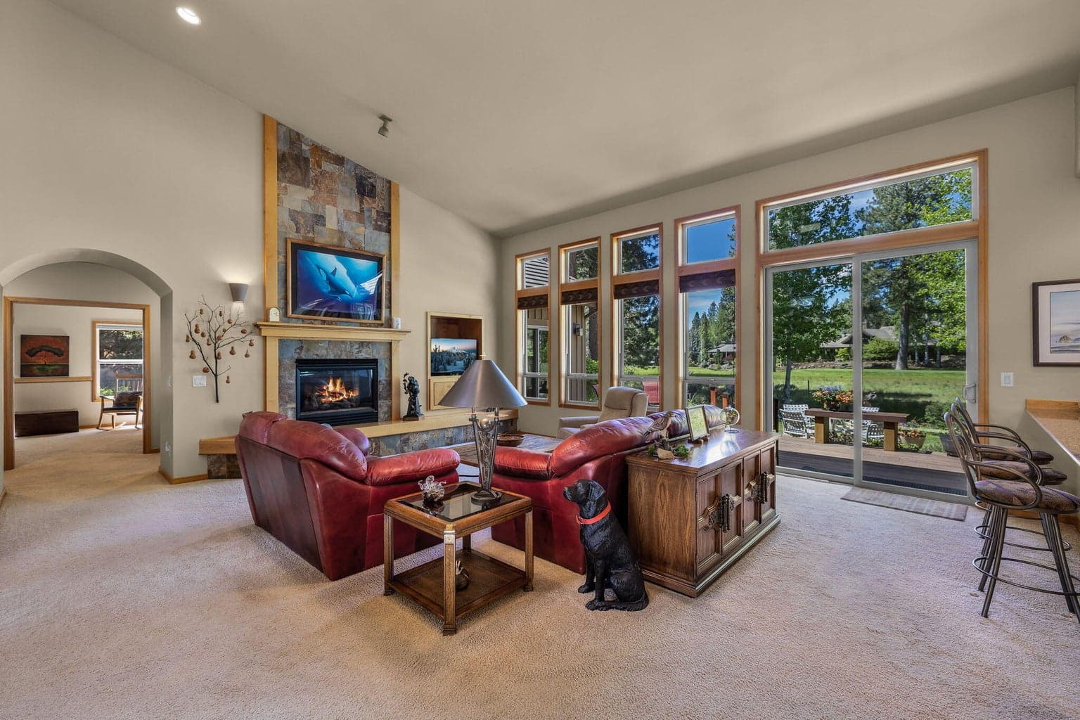 The spacious great room features high ceilings, expansive windows, and a comfortable connection to the private fairway setting beyond.