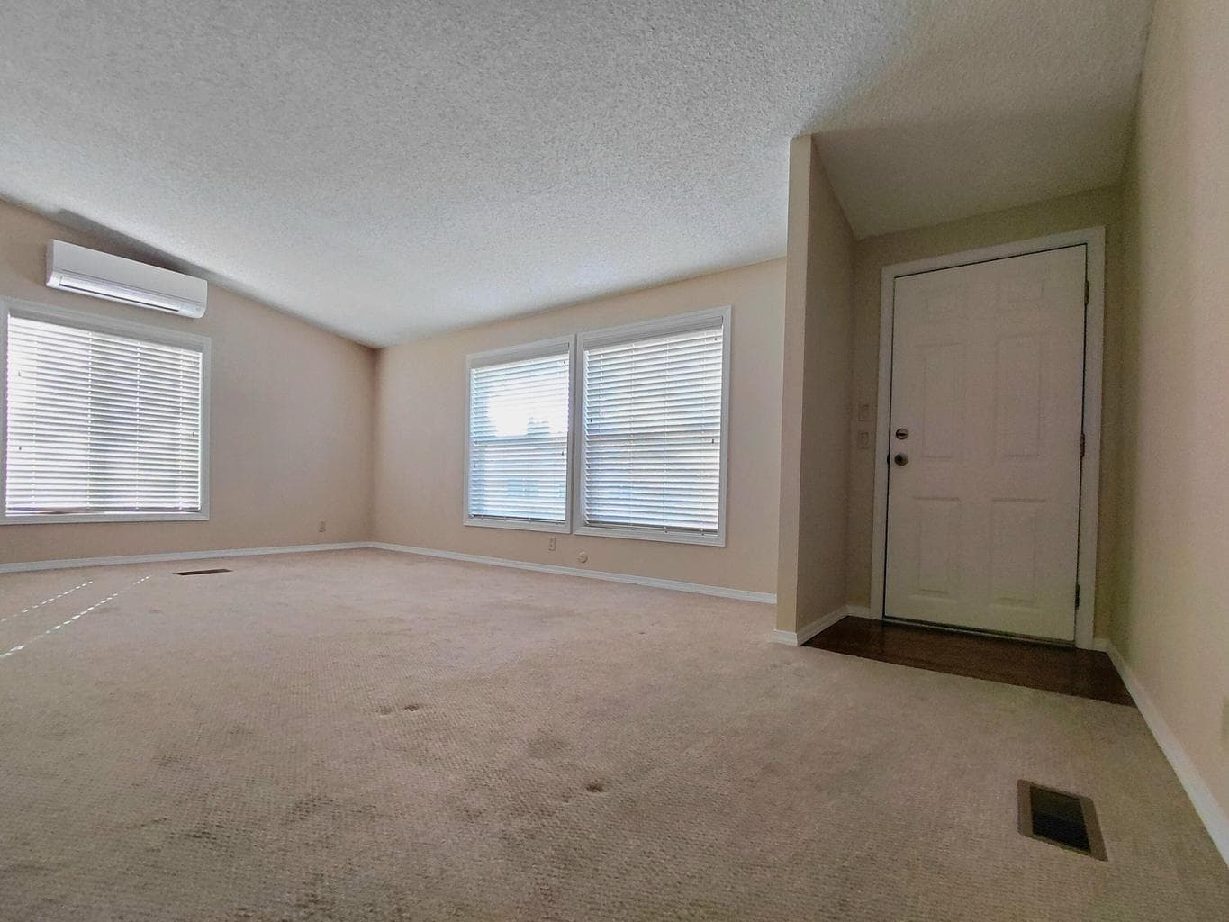 Comfortable living room has textured walls and newer carpet.