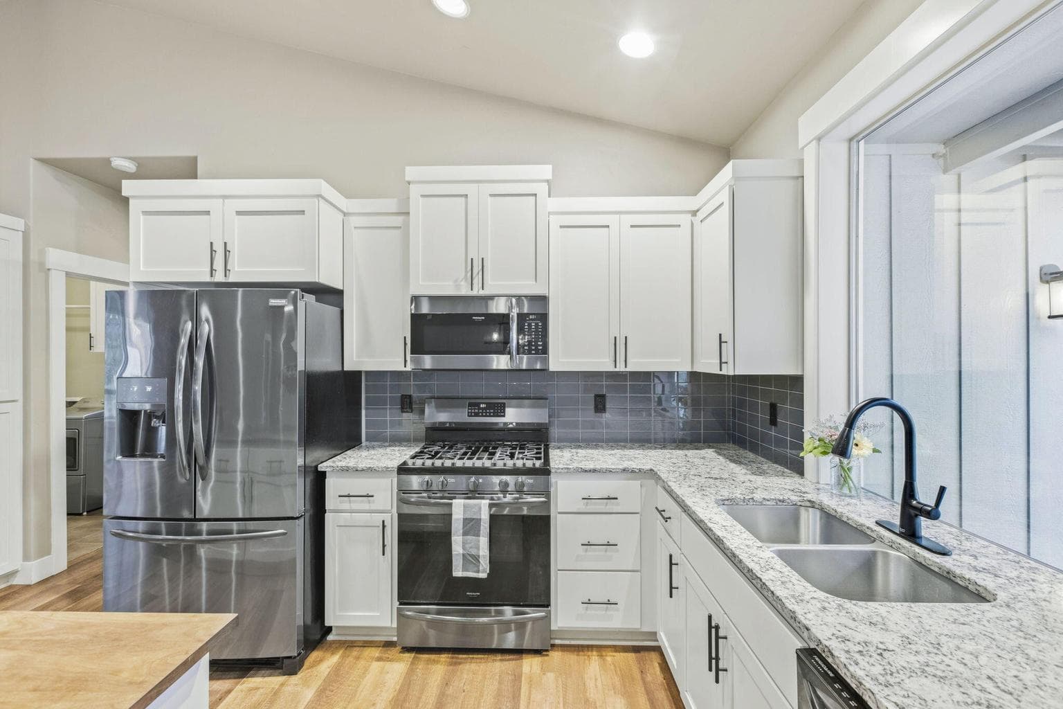 Kitchen with granite counters, tile backsplash, and window views.