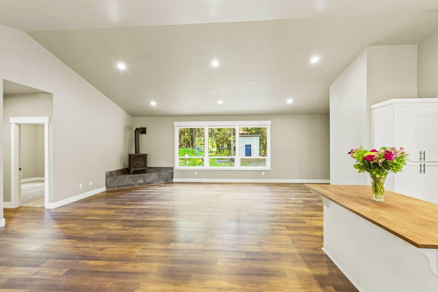 Virtually staged great room with fireplace and forested views.