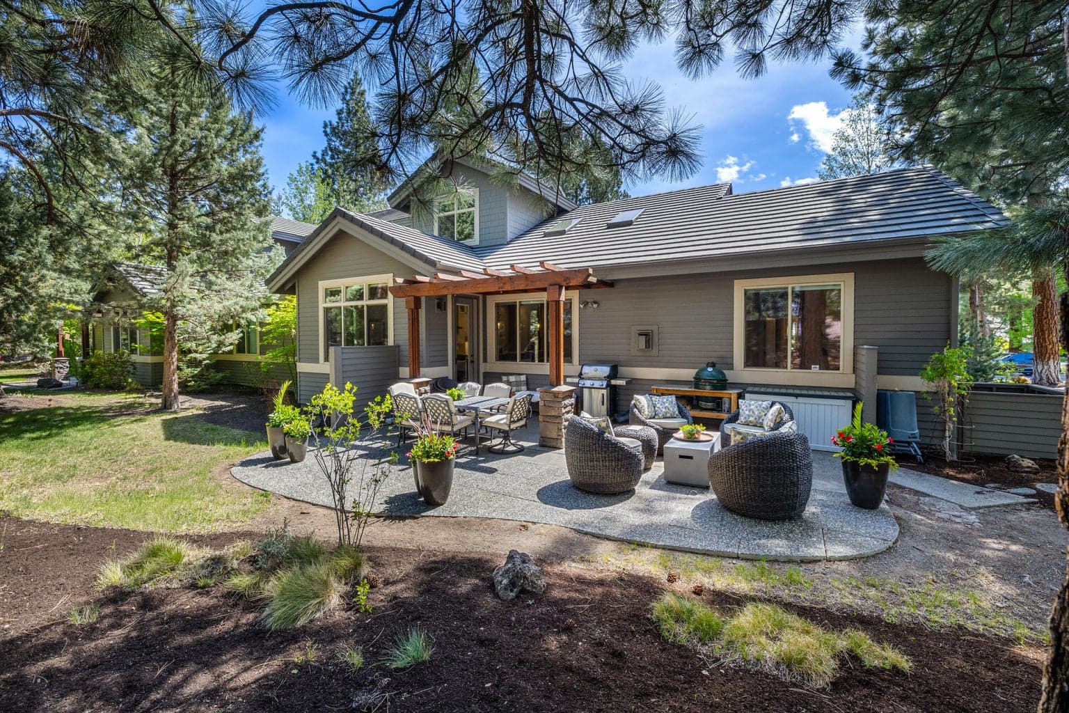 An expanded rear patio and refreshed landscaping create a private outdoor retreat, with multiple seating areas, grilling space and a peaceful setting beneath the surrounding pines.