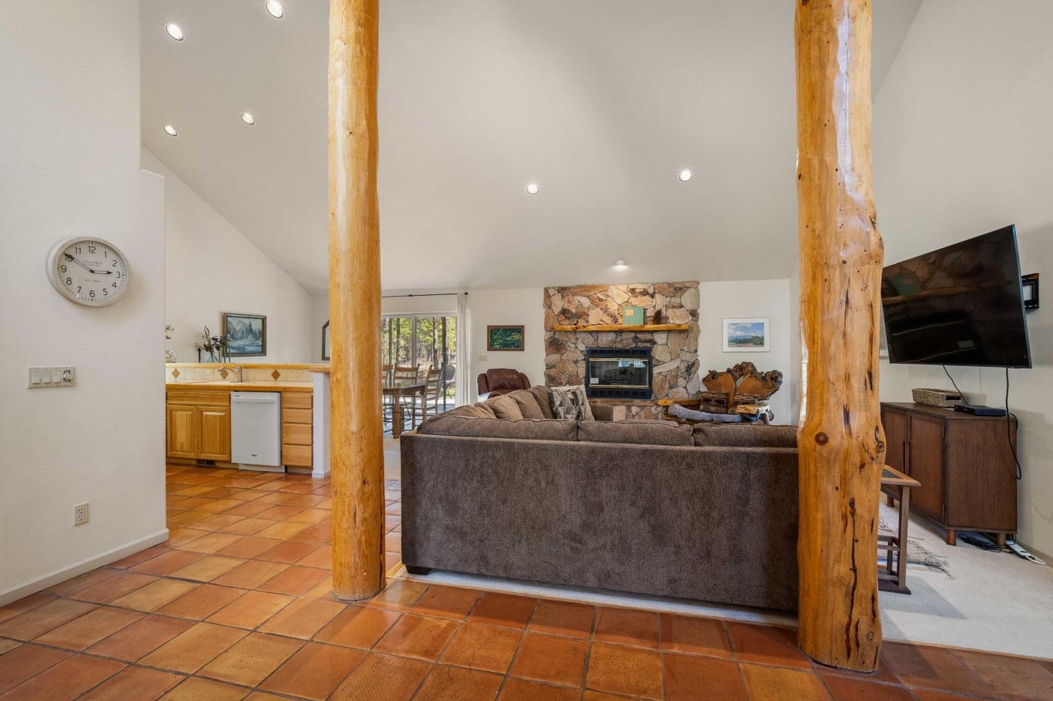 Open great room view from the entry, highlighting vaulted ceilings, timber posts, tile flooring, and warm Central Oregon character.