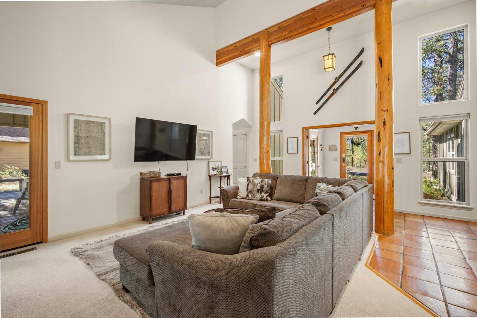 Vaulted living area with tall windows, wood beams, and natural light reflecting the wooded Sunriver setting.