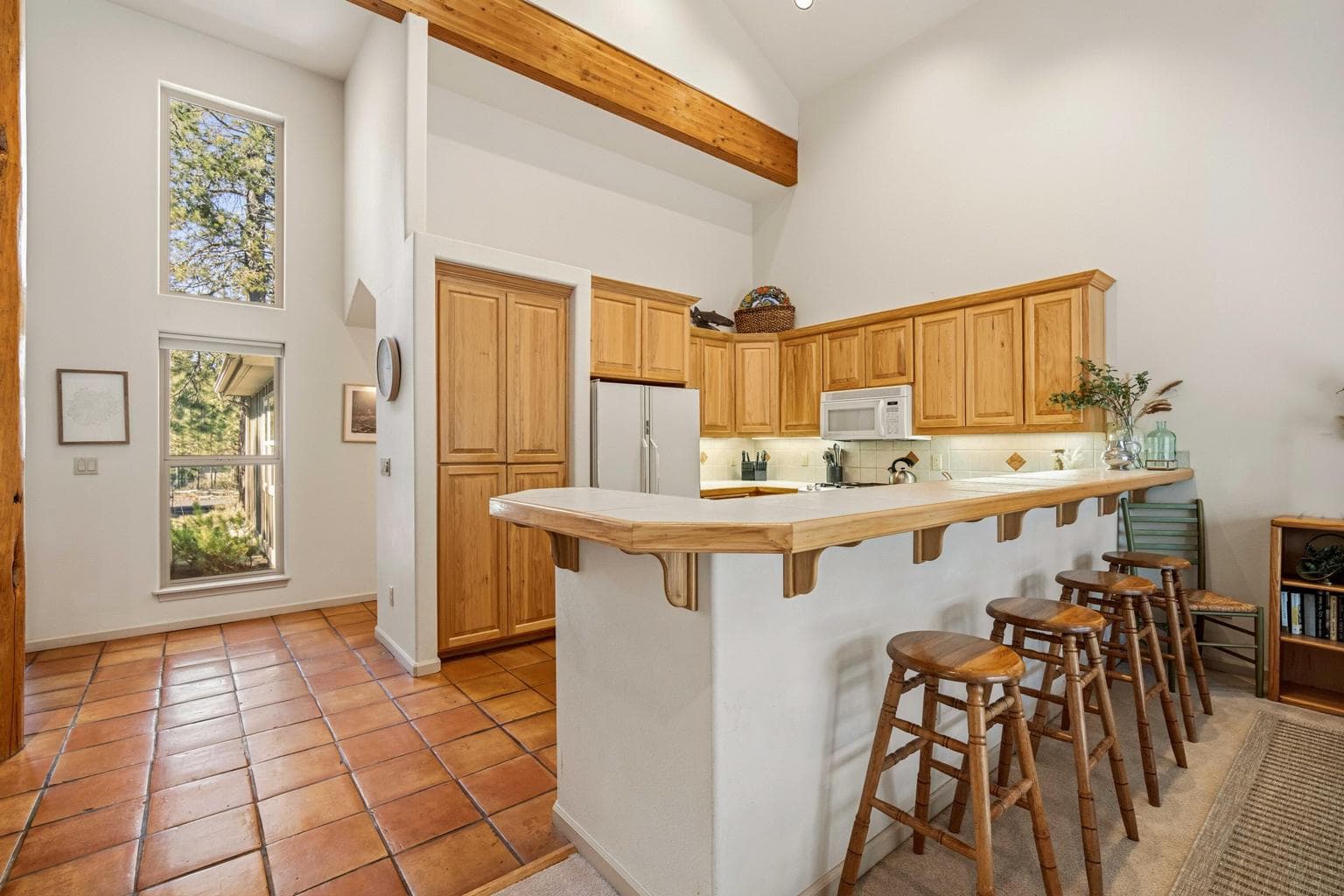 Kitchen breakfast bar with wood cabinetry, vaulted ceiling, and open sightlines to the dining and living areas.