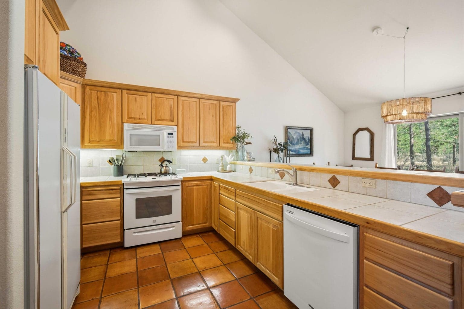 Kitchen workspace with wood cabinetry, tile counters, gas range, and easy connection to the main living areas.