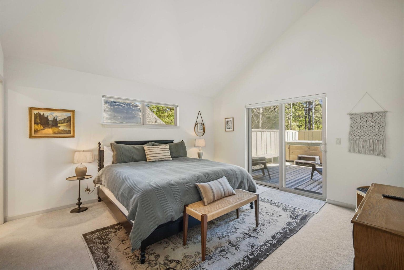 Spacious bedroom suite with vaulted ceiling, deck access, and peaceful views toward the natural Sunriver setting.