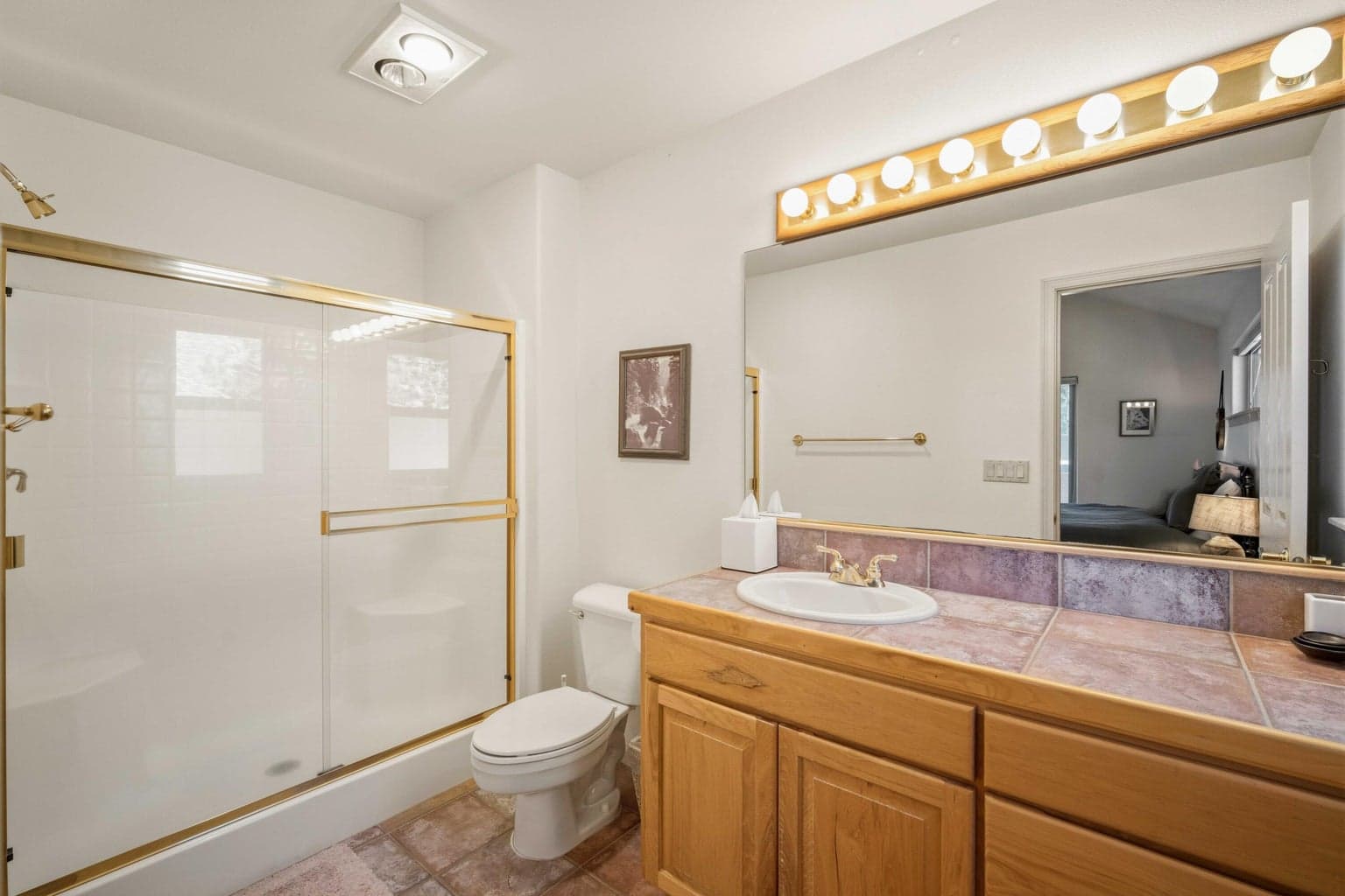Suite bathroom with tile vanity, large mirror, and tub-shower combination serving one of the home’s bedroom suites.
