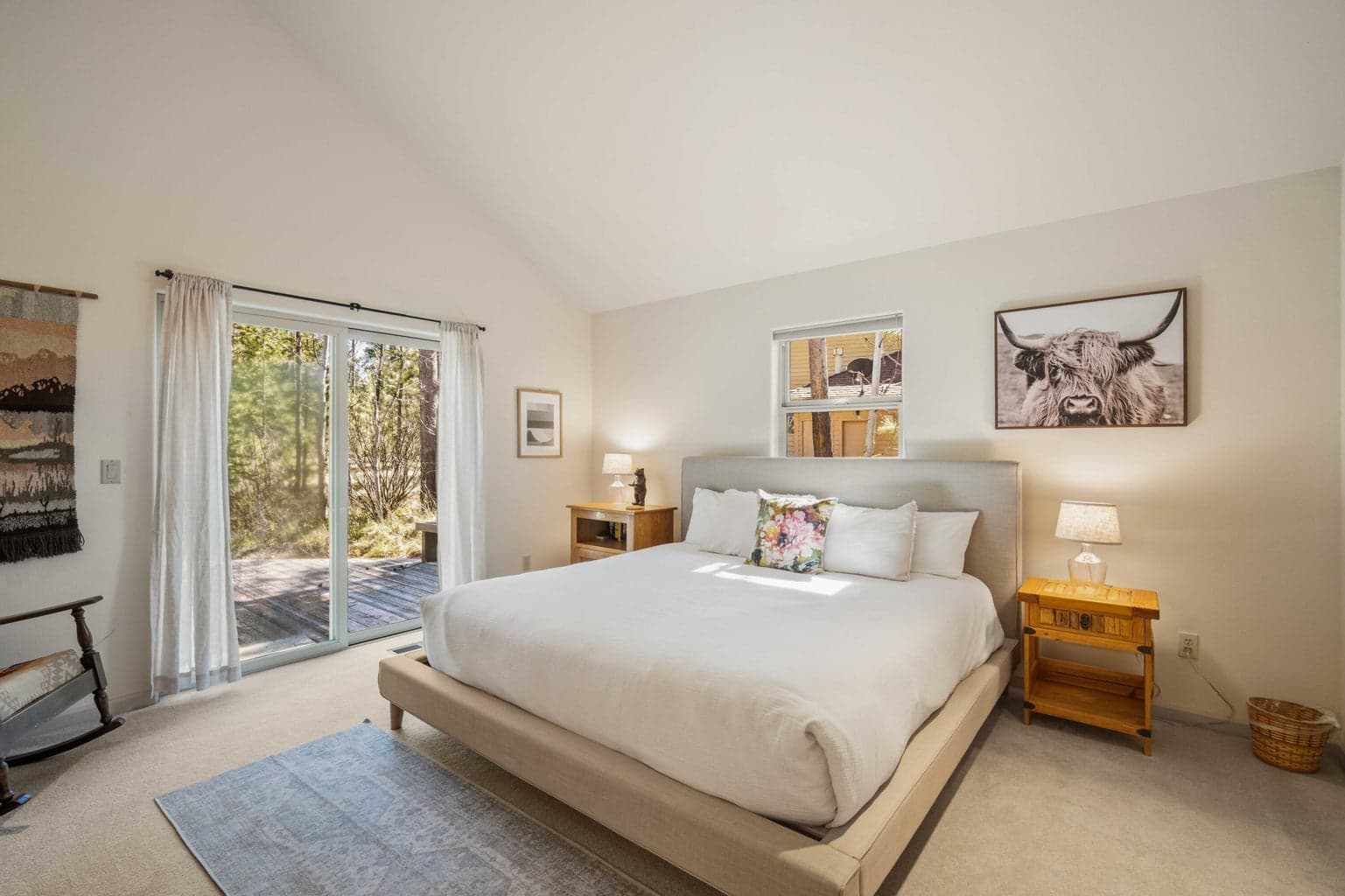 Second bedroom suite with vaulted ceiling, deck access, and soft natural light from the wooded Sunriver surroundings.