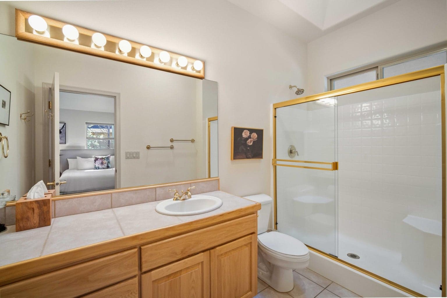 Bathroom serving the second suite, with tile vanity, large mirror, and shower-tub combination.