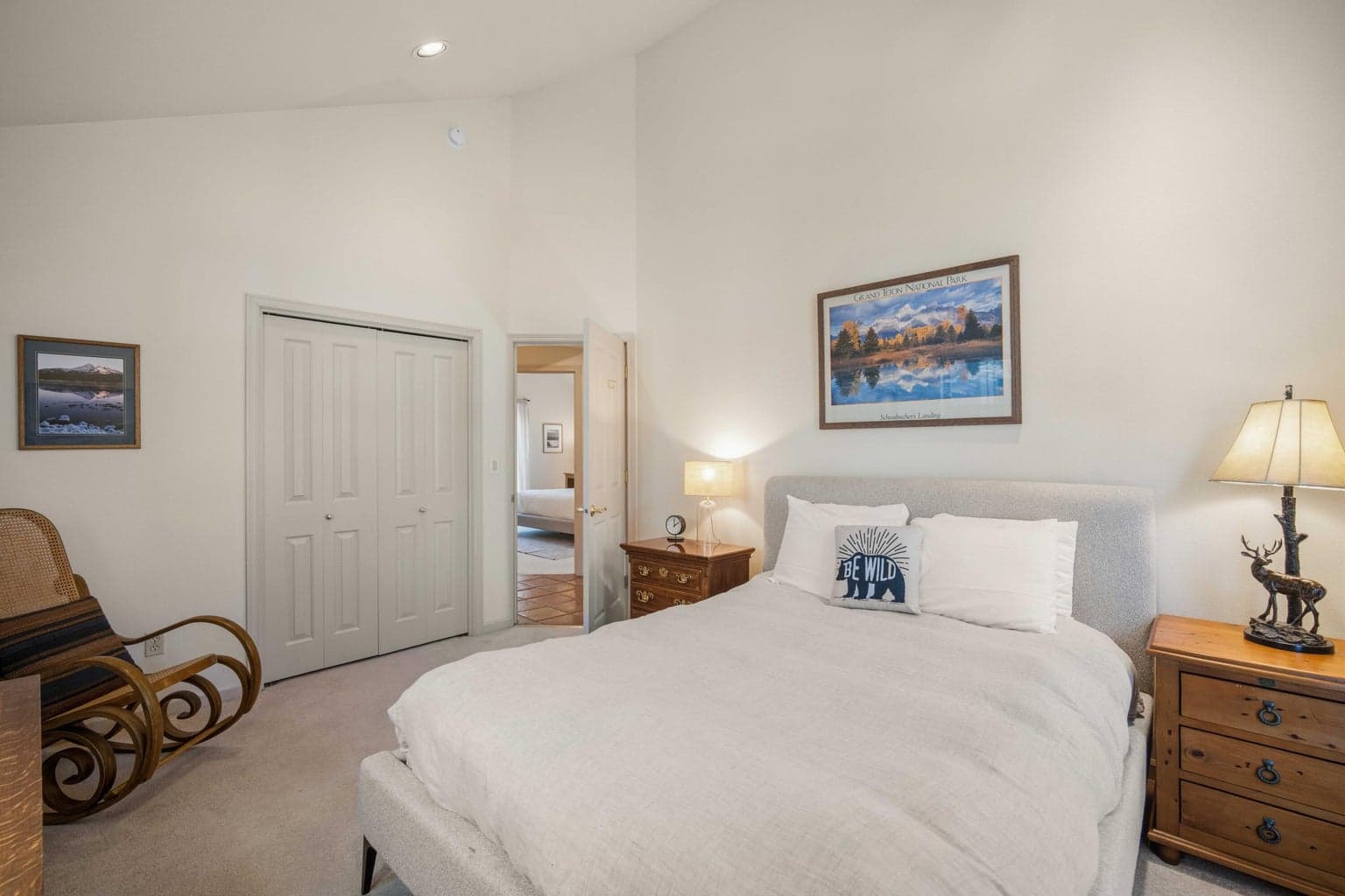 Guest bedroom with vaulted ceiling, treed window views, and a comfortable Central Oregon resort-home feel.