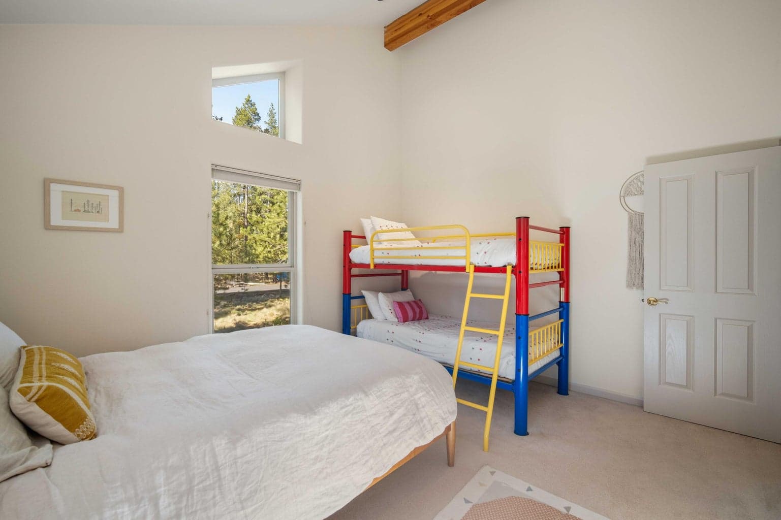 Bunk bedroom with additional bed space, vaulted ceiling, and windows toward the natural Sunriver setting.