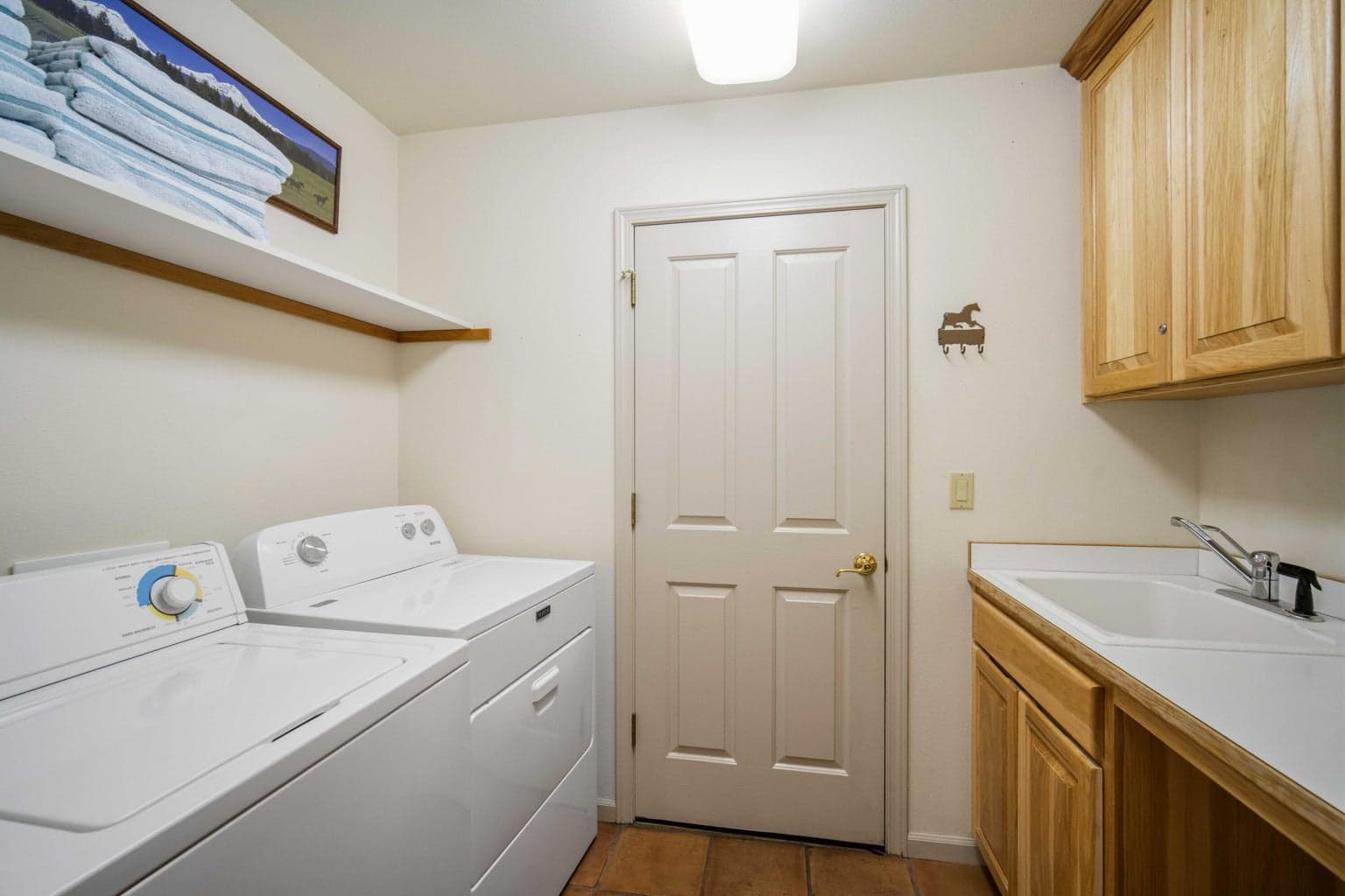Laundry room with washer, dryer, utility sink, cabinetry, and tile flooring for practical Sunriver home function.