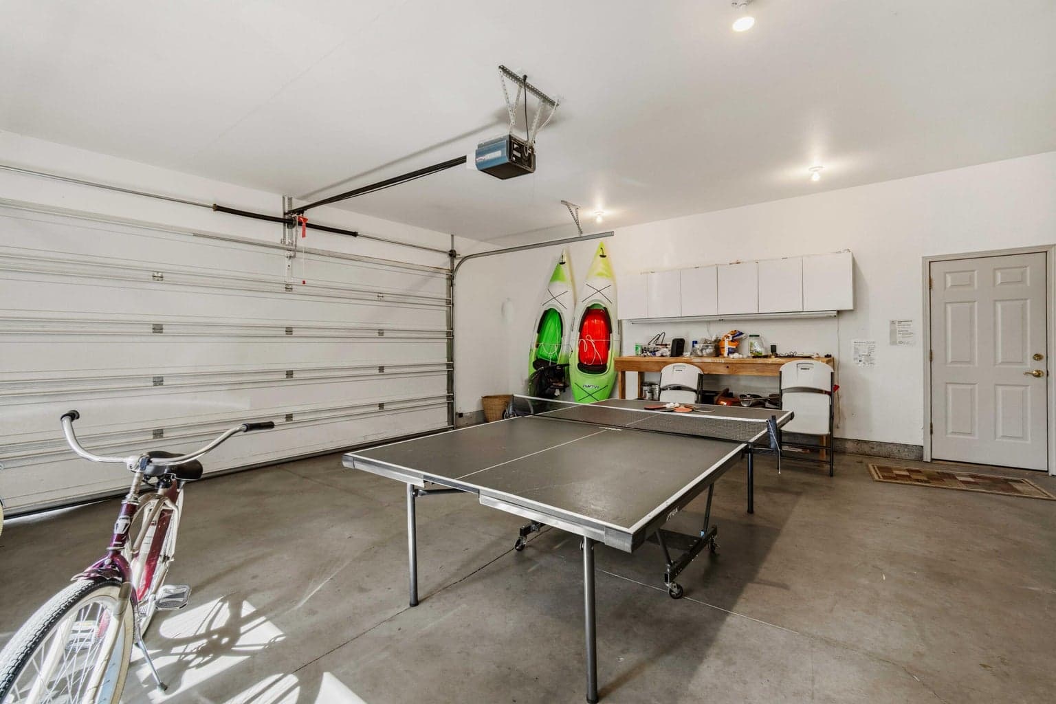 Two-car garage currently arranged for recreation and storage, with ping pong, bikes, kayaks, and Central Oregon gear space.