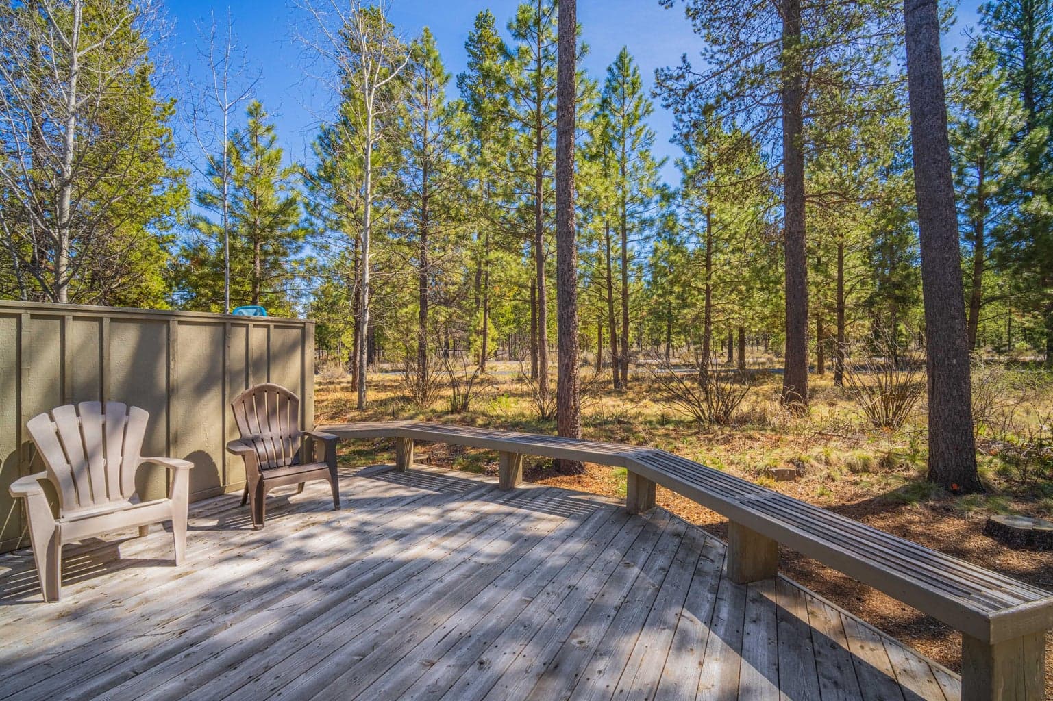 Back deck seating area surrounded by native pines and natural landscaping in Sunriver, Oregon.