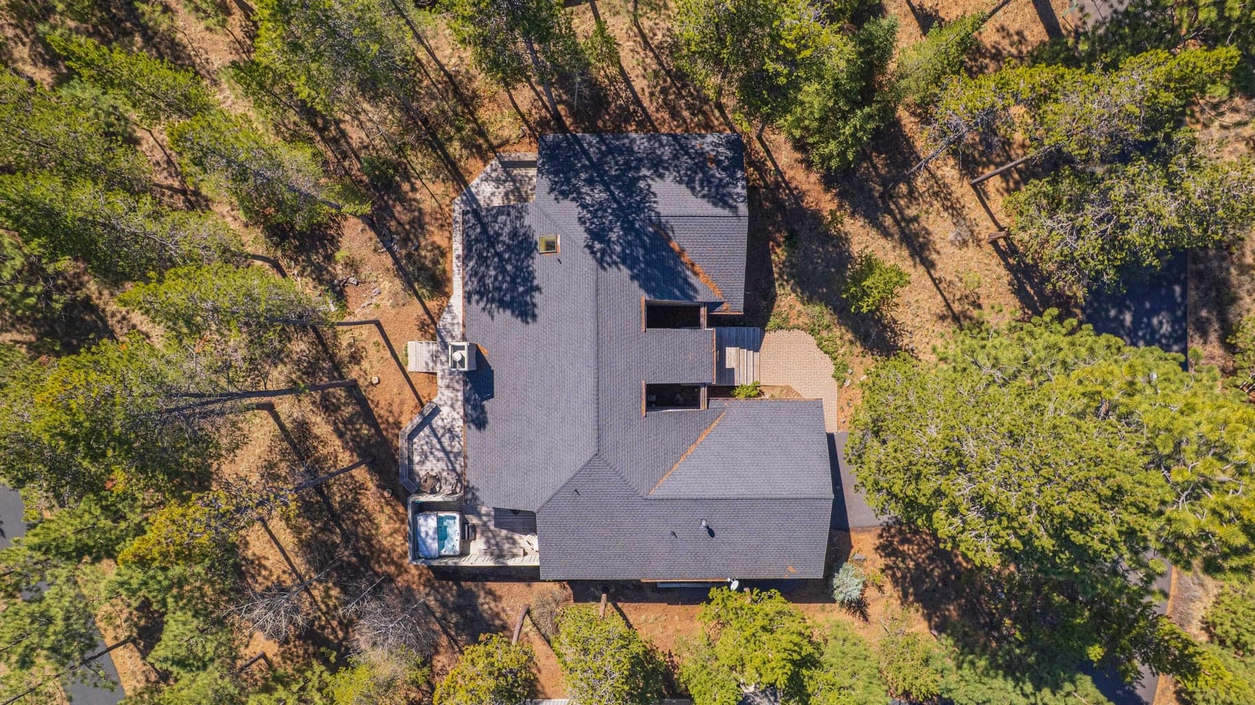Overhead aerial view of the home, roofline, deck layout, driveway, and surrounding trees in Sunriver.