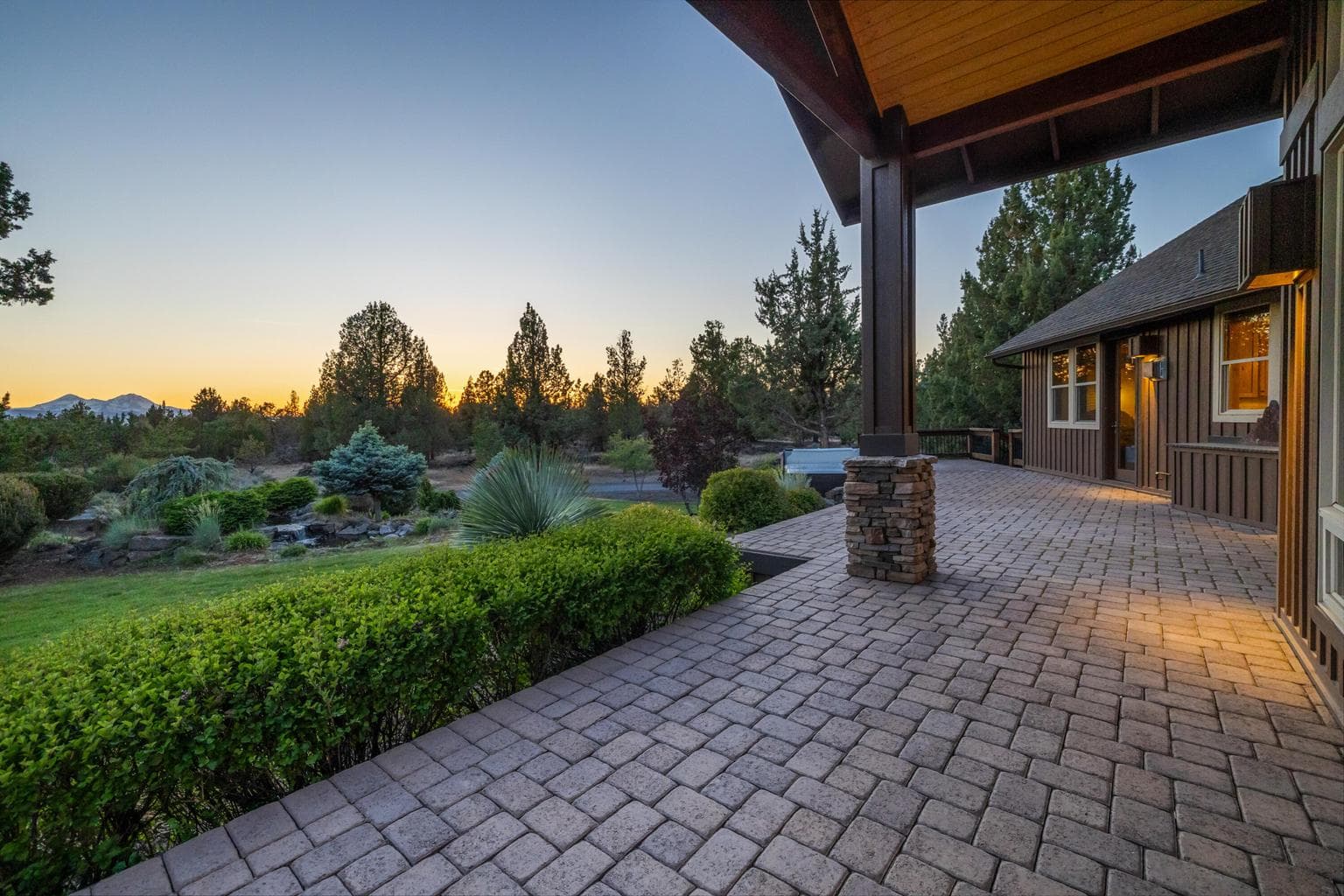 A generous covered paver patio extends the living space outdoors, offering a peaceful place to take in the landscaped grounds, evening light and sweeping Cascade Mountain view setting.