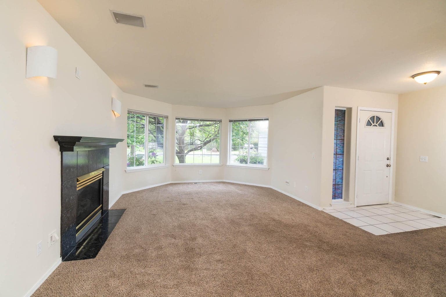 Large Living room area with gas fireplace and bay window facing to the from of home!
