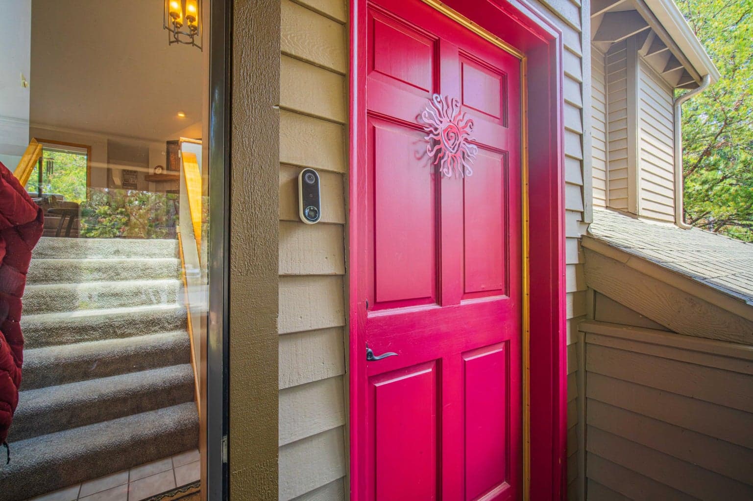 Distinctive red front door with covered entry and smart doorbell.