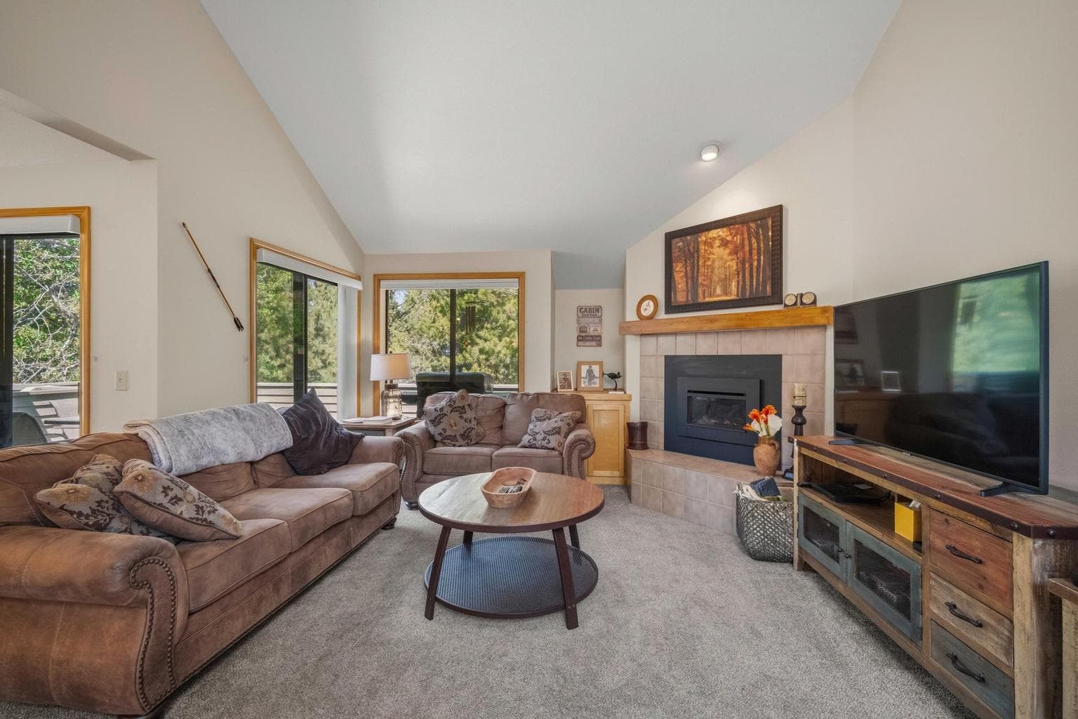 Vaulted great room with gas fireplace, large windows, and access toward the deck.