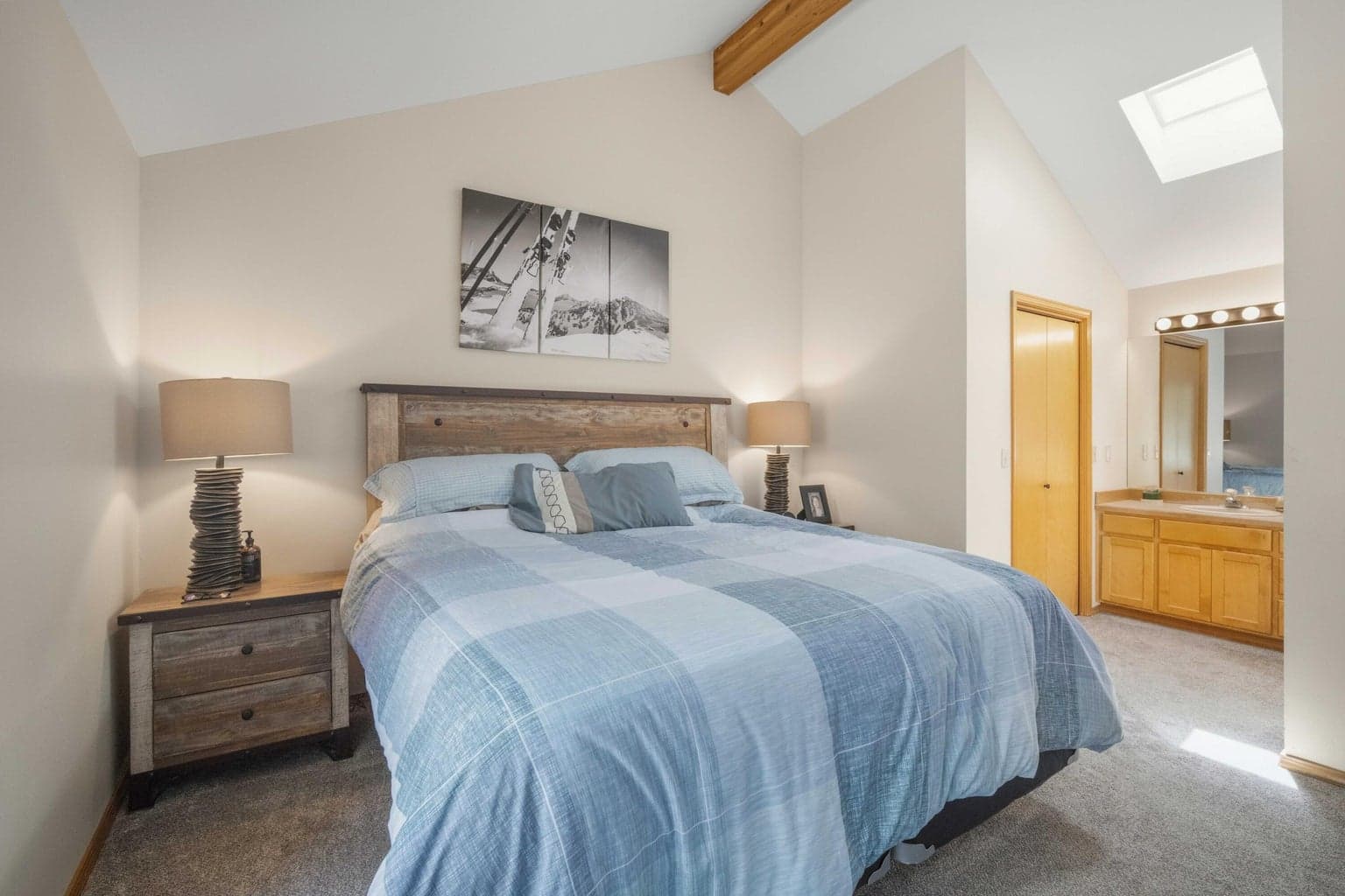 Primary suite with vaulted ceiling, skylight, and bath access.