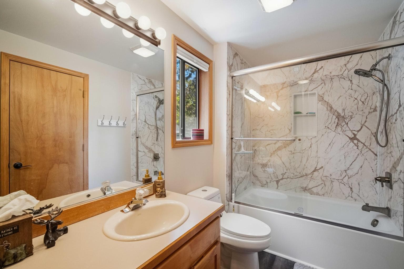 Lower full bathroom with updated tub surround and newer toilet.