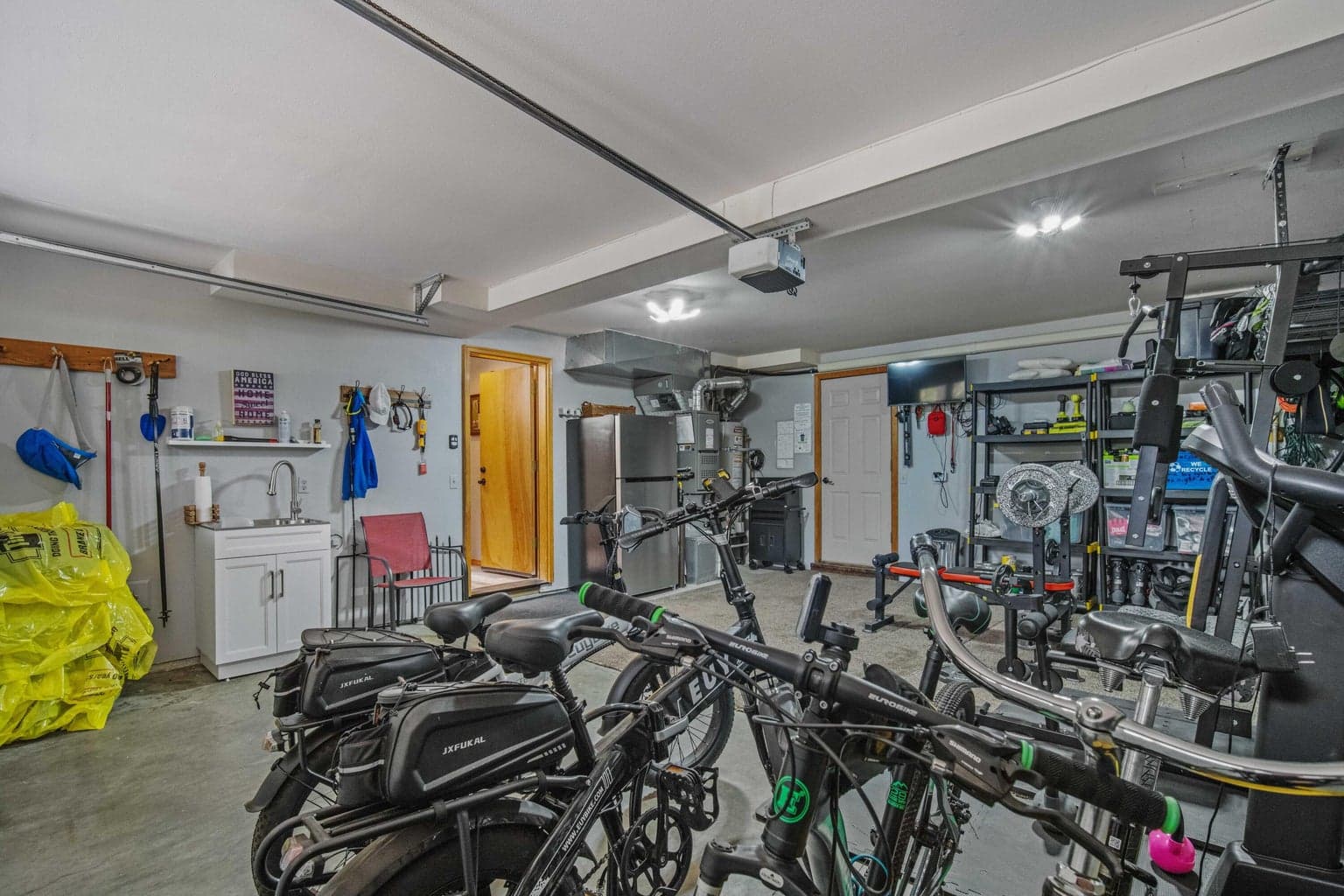 Garage utility area with added sink, storage, and space for bikes and tools.