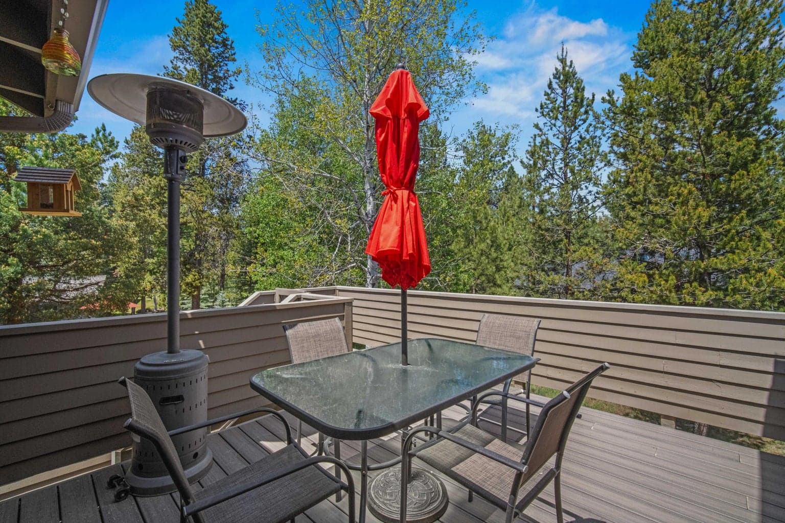 Upper Trex deck with dining space, tree views, and outdoor heater.