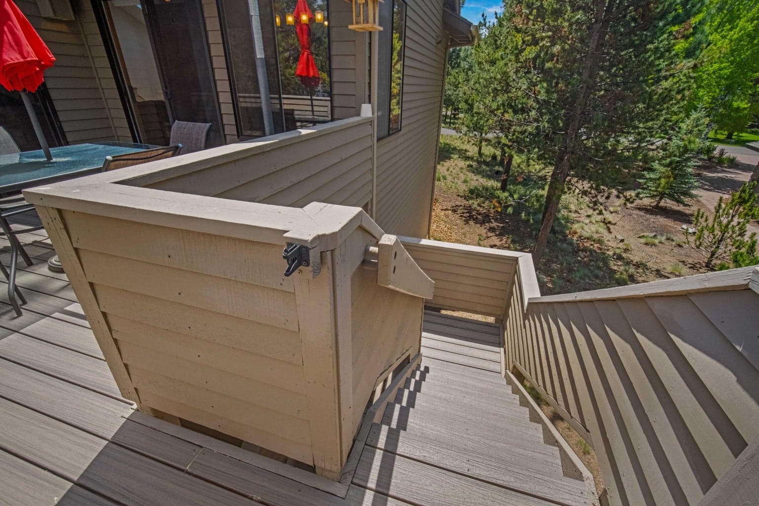 Updated deck stairs connect the upper outdoor living area to the lower covered patio.