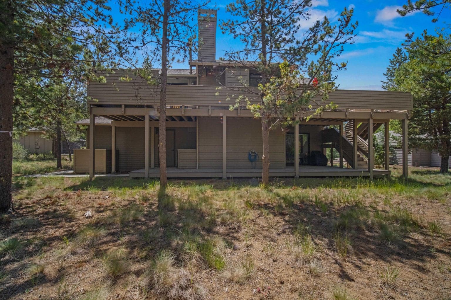 Back exterior highlights the two-level deck configuration and wooded setting.