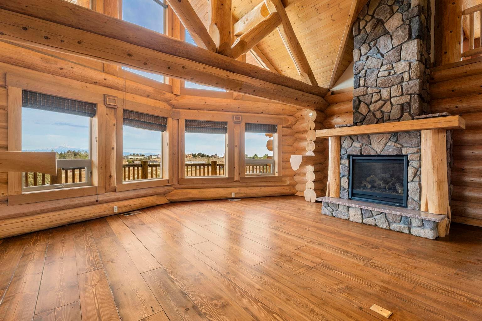 A wall of windows in the living room with rock wall propane fireplace