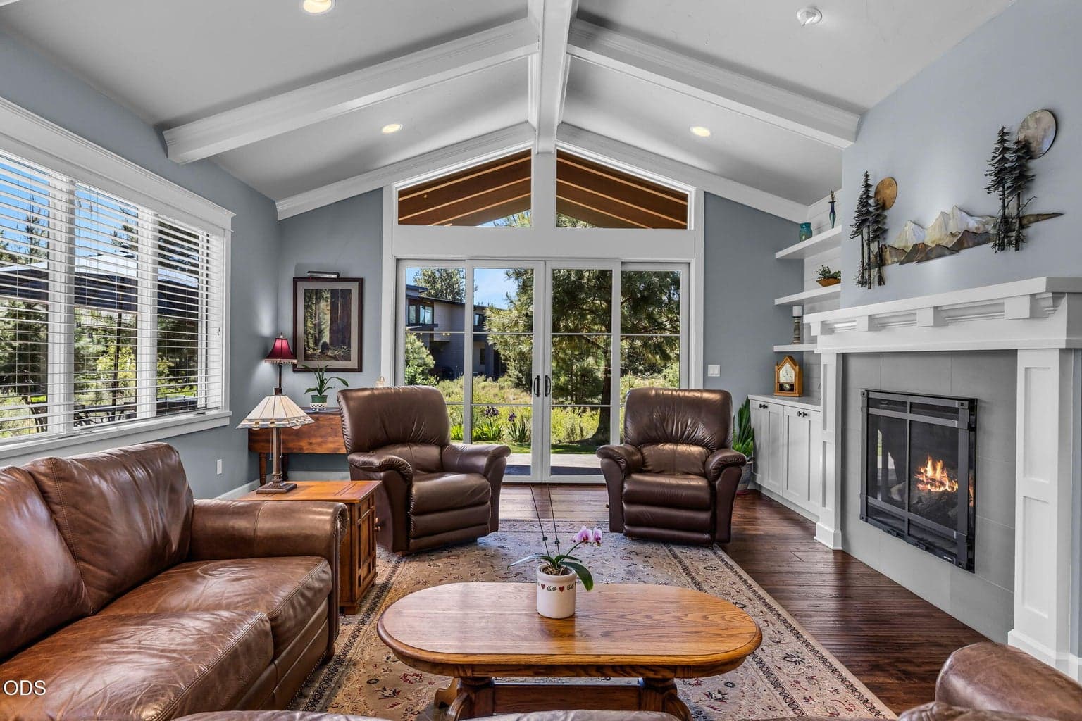 Light-filled great room with vaulted ceilings, broad windows, French doors, fireplace, and seamless connection to the outdoor living area.