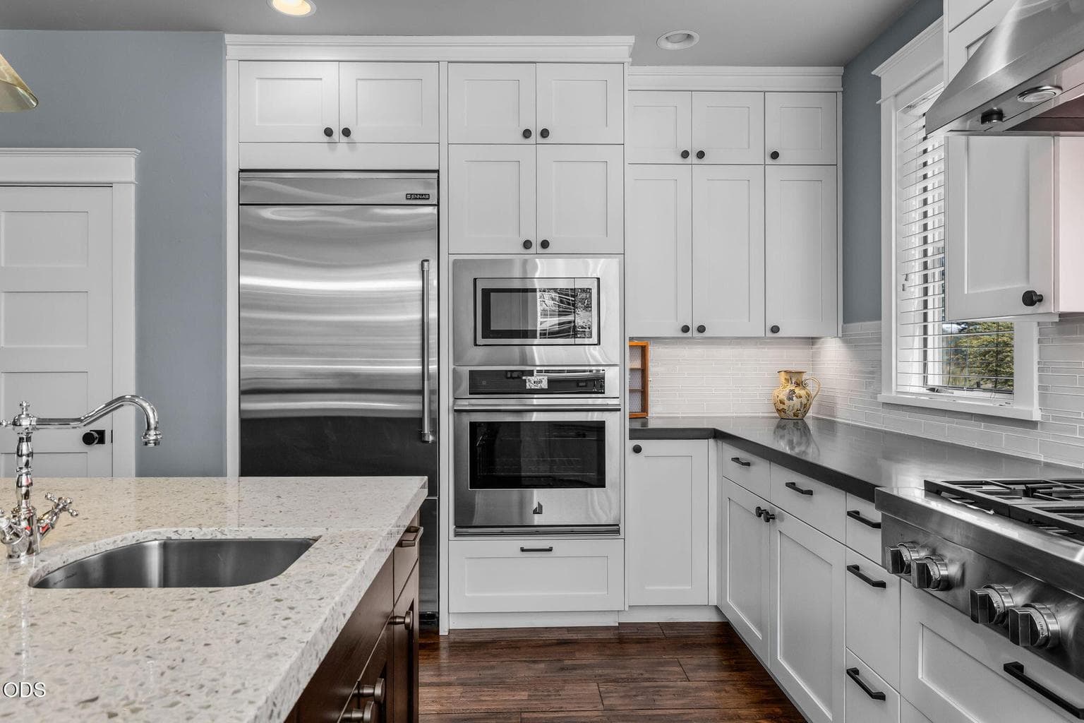 Well-designed kitchen with JennAir appliances, extensive cabinetry, tile backsplash, solid-surface counters, and thoughtful workspace.
