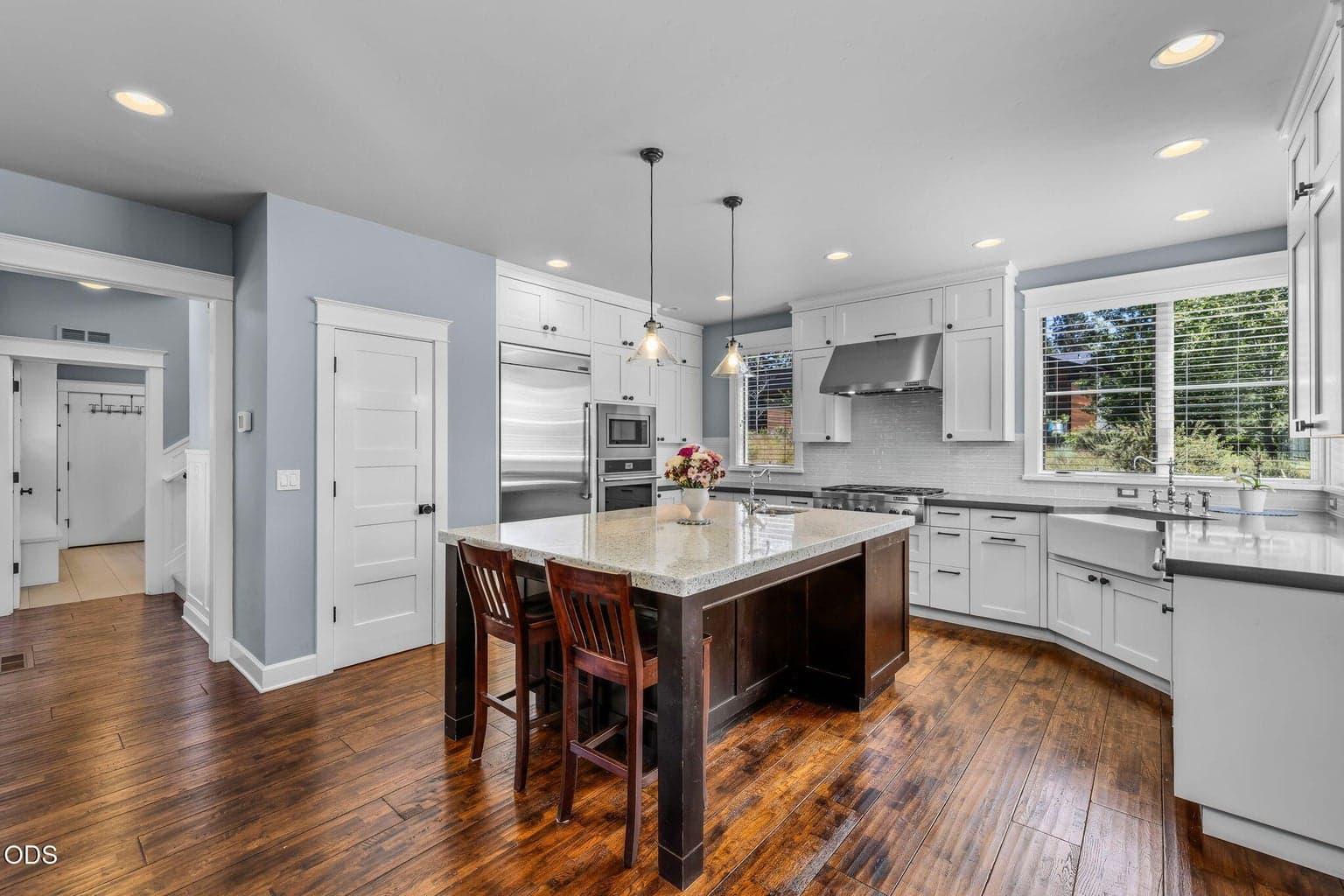 Beautifully appointed kitchen with large island, custom cabinetry, stainless appliances, farmhouse sink, and warm wood flooring.