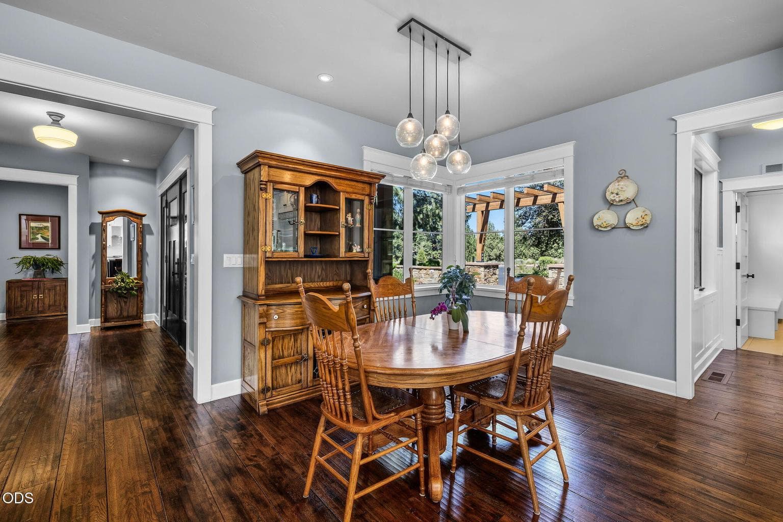 Inviting dining space with modern pendant lighting and windows overlooking the landscaped courtyard and stone patio wall.