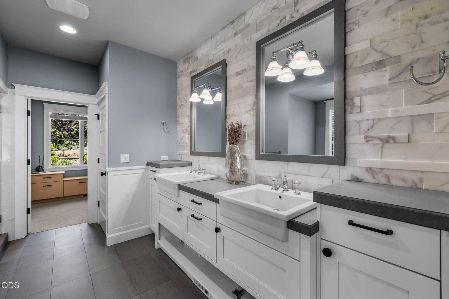 Beautifully finished bath with crisp white cabinetry, tile flooring, framed mirror, and a glass-enclosed walk-in shower.