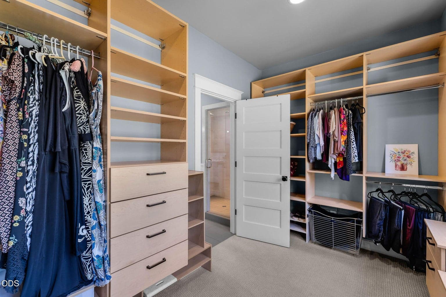 Spacious walk-in closet with custom built-in drawers, hanging storage, open shelving, and a large window overlooking the courtyard.