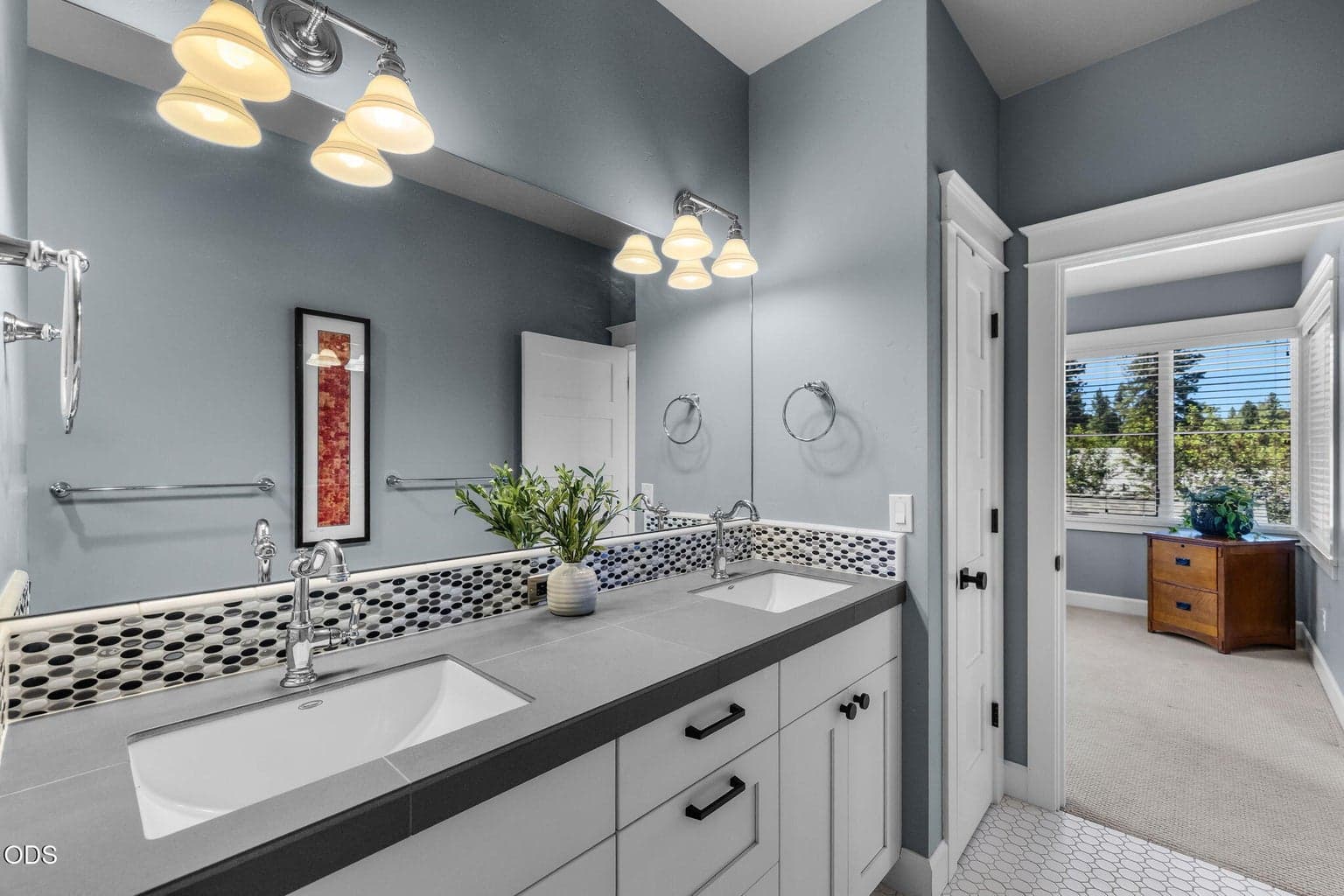 Well-appointed upper-level full bath with dual sinks, tile flooring, decorative backsplash, and convenient access from the guest rooms and bonus room.